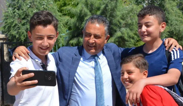Kırıkkale Milli Eğitim Müdürü Rahmi Güney, öğrencilerle okul bahçesinde fotoğraf çektiriyor.